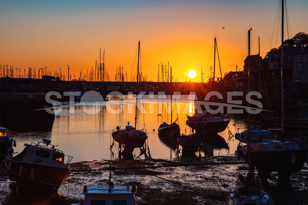 Picturesque image of a warm dawn sunrise as the tide comes in at Brixham Harbour.