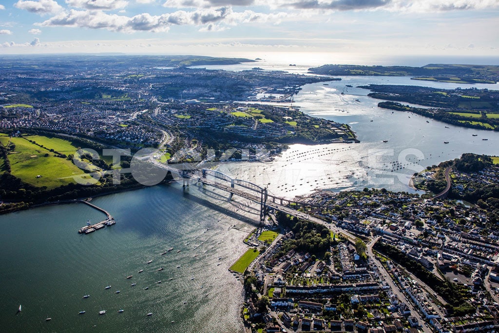 Aerial image of the Tamar Bridge in Plymouth, Devon, agaist the sun shining on the water with a long distance view out to sea.