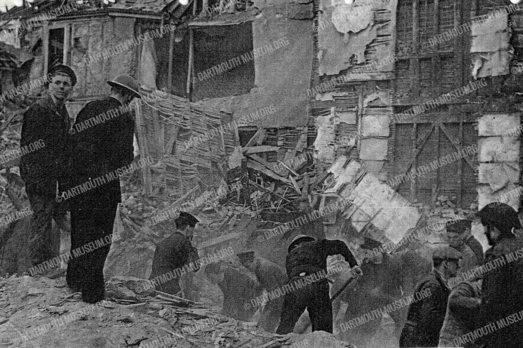 Historical photograph of the ruined premises in Duke Street after German Bombs dropped in February 1943, showing Army, Navy and ARP men searching for survivors.