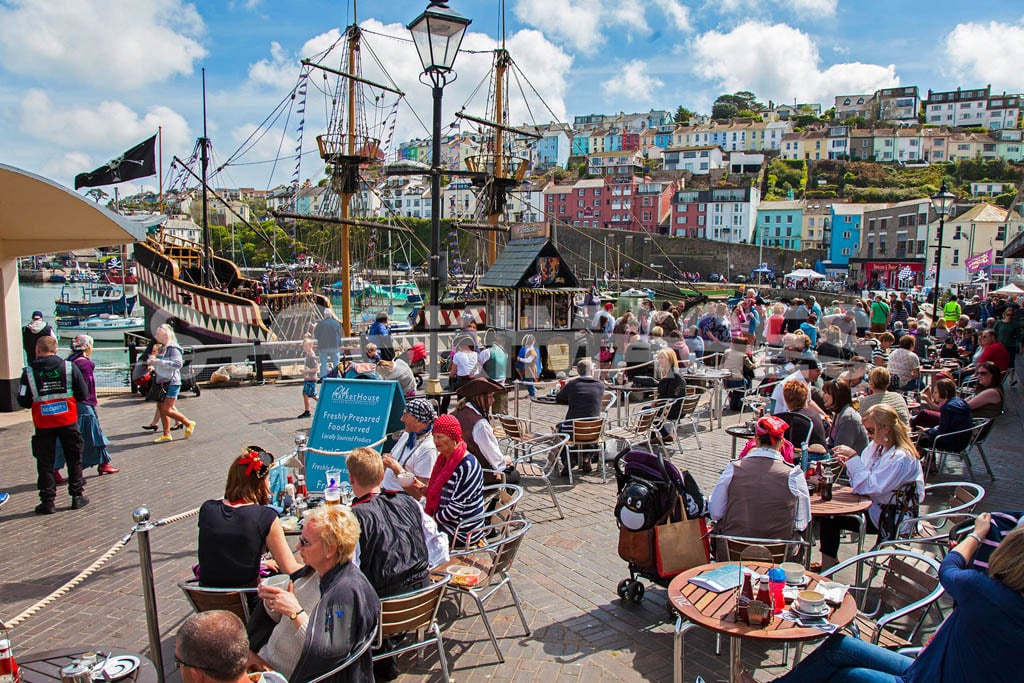 A busy scene of visitors of the Brixham Pirate Festival enjoying the sunshine by the Golden Hind Ship.