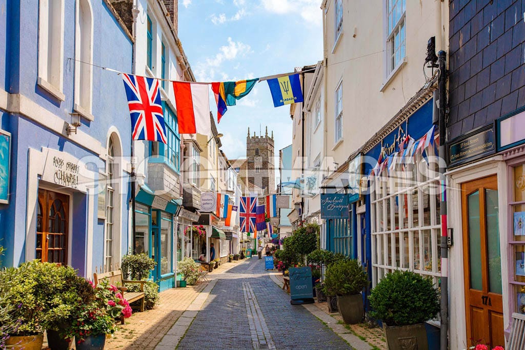Image of Dartmouth's iconic Foss Street - a popular destination to shop - under many flags looking towards St Saviours Church.