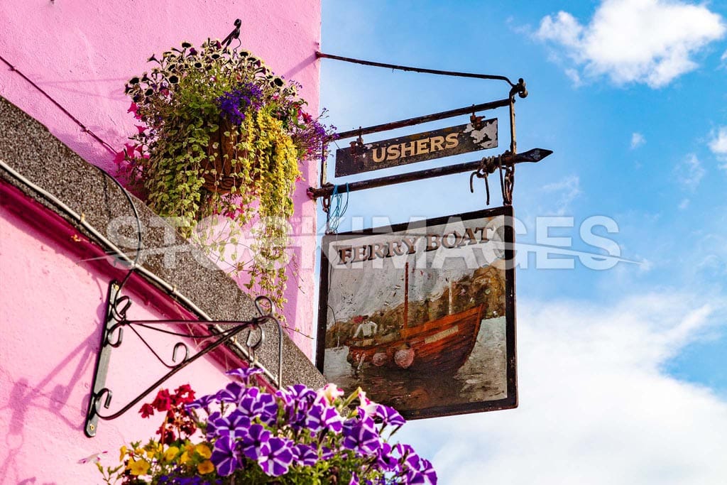 Image of the Ferry Boat Inn sign surrounded by colourful flowers against a blue sky.
