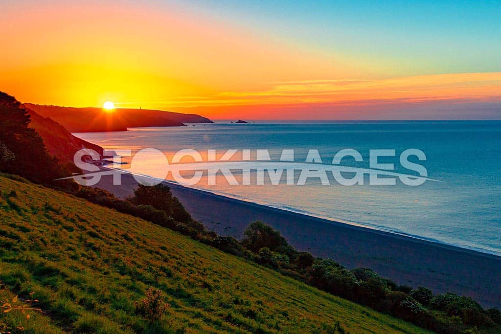 A colourful sunrise next to the Dayrmark over Strete Gate beach and coastline.